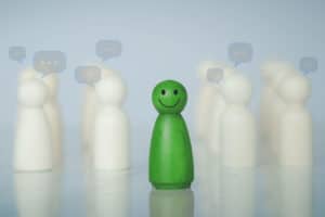 featured image of blogpost Career Tips for Introverts: The Right Job Green wood figure with happy face standing out from the crowd of different people. Individuality, Introvert, Not care when someone is talking, Unique human shape, Leadership, Human resource.