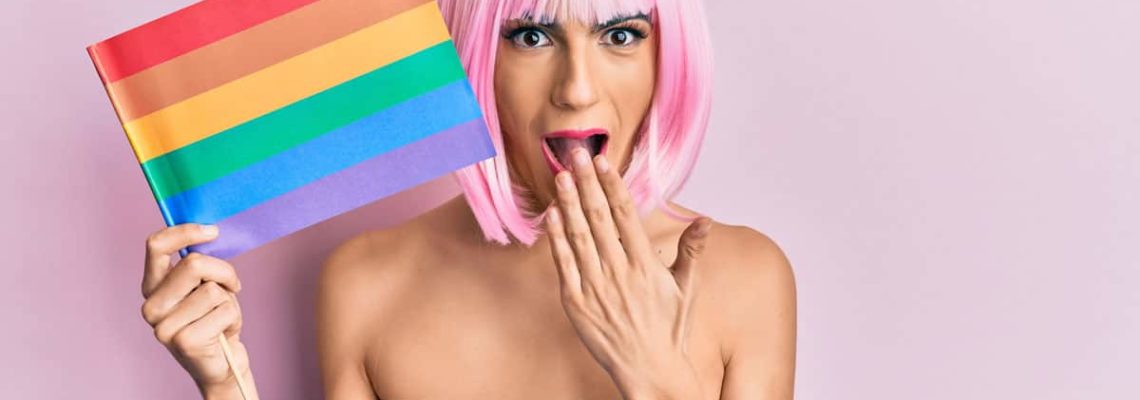 Young man with rainbow flag, pink wig and make-up; Young,Man,Wearing,Woman,Make,Up,Holding,Rainbow,Lgbtq,Flag