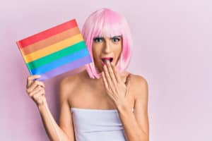 Young man with rainbow flag, pink wig and make-up; Young,Man,Wearing,Woman,Make,Up,Holding,Rainbow,Lgbtq,Flag